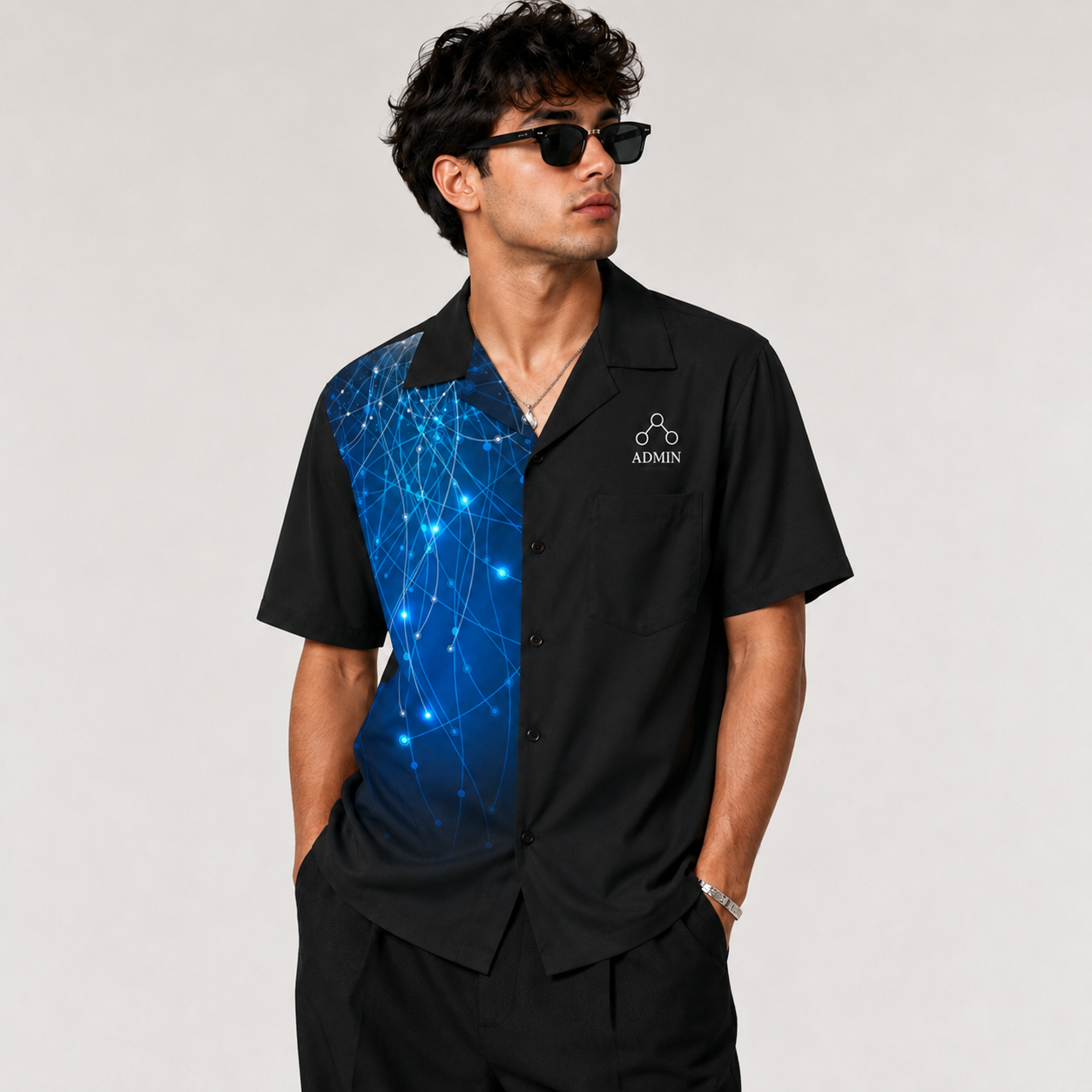 A man wearing a black short-sleeve button-up shirt with a blue digital network pattern on the left side and a white 'ADMIN' logo on the chest, paired with black pants and sunglasses, against a light gray background.