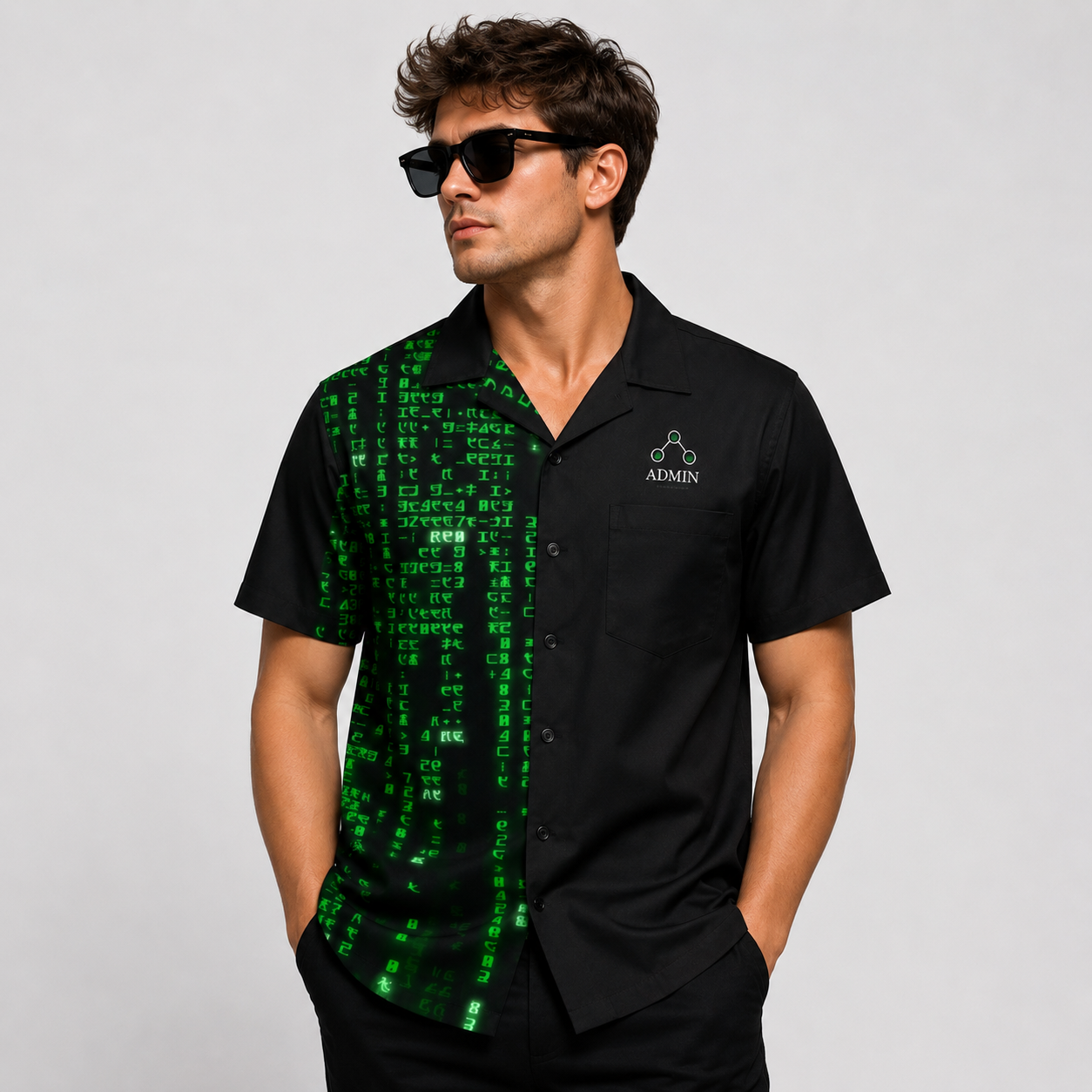 A man wearing a black short-sleeve button-up shirt with a green digital matrix-style print on the left side, featuring a white 'ADMIN' logo on the chest, set against a plain light gray background.